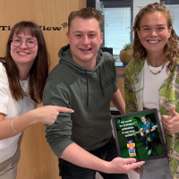 Drie mensen met een fotolijstje.