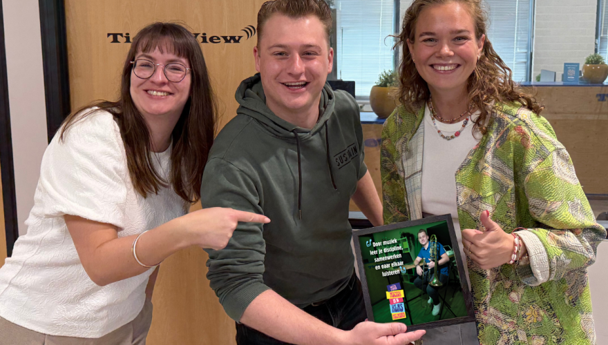 Drie mensen met een fotolijstje.